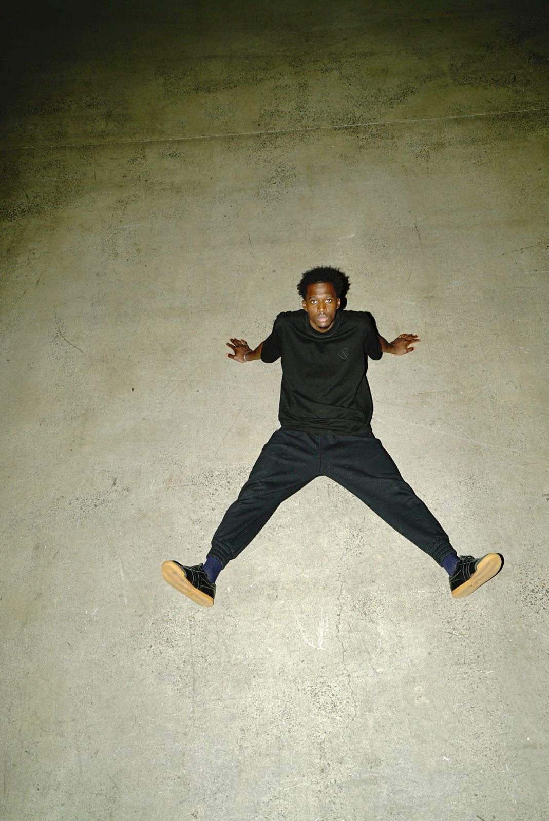 Black broad collar tee with tonal logo — movement campaign photograph